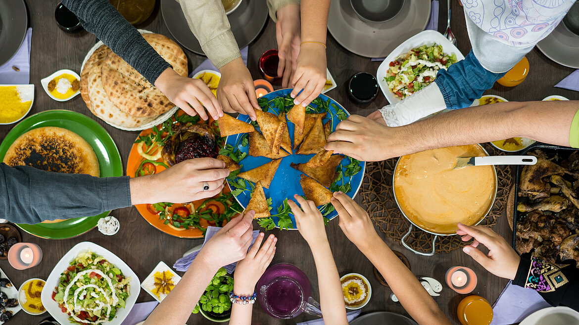 Tisch mit arabischem Essen, viele Hände greifen zu