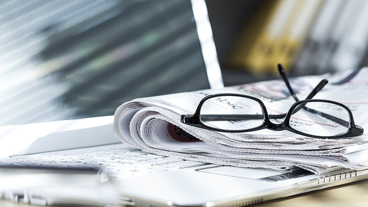 Laptop und Zeitung auf einem Schreibtisch